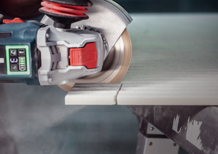 Elektrisk såg kapar genom en träplanka med dammoln runt klingan.