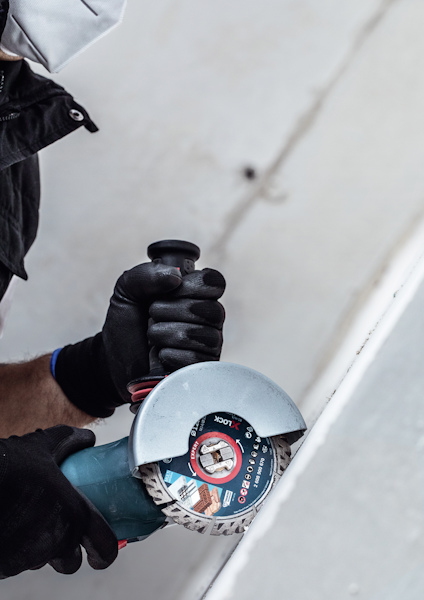 Person använder vinkelslip med svart handske.