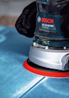 En person slipar en blå yta med en Bosch GEX 125-150 AVE excenterslipmaskin.