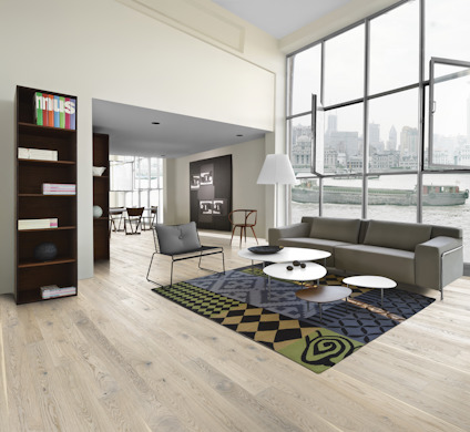 Modernt vardagsrum med grå soffa, mönstrad matta, runda soffbord och stora fönster med utsikt över en stadssilhuett.