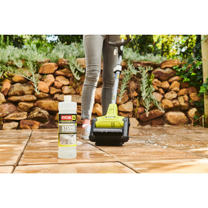 Person rengör stengolv med en RYOBI-maskin, en flaska stenrengöringsmedel står i förgrunden.