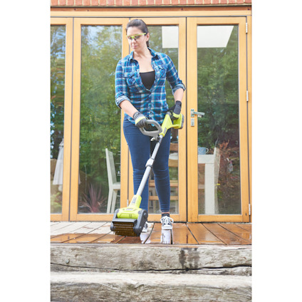 Person som använder en eldriven skrubbmaskin för att rengöra en trätrappa framför en altandörr.