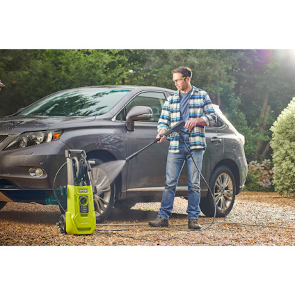 En person använder en högtryckstvätt för att tvätta en SUV utomhus.