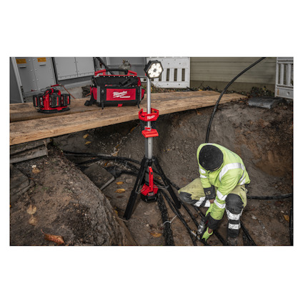 Arbetare i högreflekterande kläder arbetar i ett dike med verktyg och utrustning från Milwaukee på marken.