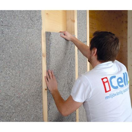 Person monterar isoleringsskiva av grått material på vägg. Text på tröjan: "iCell miljövänlig isolering".