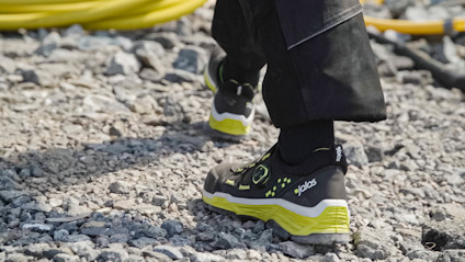 Svarta och gula skyddsskor på grusväg.