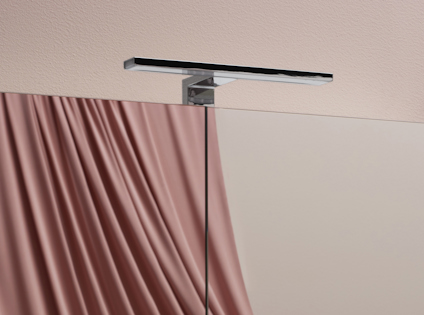 Väggmonterad silverfärgad hylla över halvt genomskinligt rosa draperi.