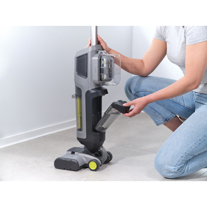 Person lossar på en vattenbehållare på en 3-i-1 skaftdammsugare av märket Ryobi.