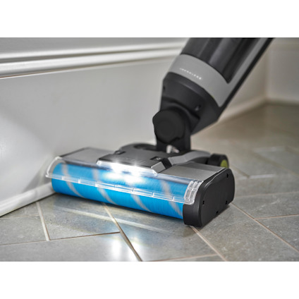 Skaftdammsugare av märket RYOBI med belyst borste på klinkergolv nära golvlist.