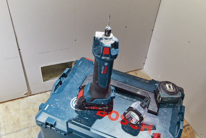 Sladdlös borrmaskin från Bosch på en verktygslåda, med måttband intill.