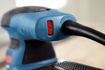 Närbild av slipmaskin med turkos kropp och röd justeringsknapp märkt med siffran "6".