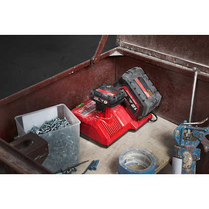 En röd laddare med ett batteri ovanpå. Omkring ligger skruvar, en plastlåda, tejprulle och verktyg.