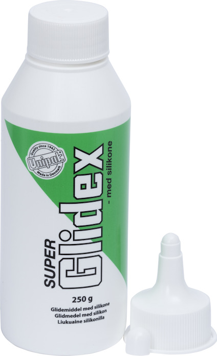Vit flaska med grön etikett, innehållande "Super Glidex" glidmedel med silikon, 250g. Flaskans kork är bredvid.