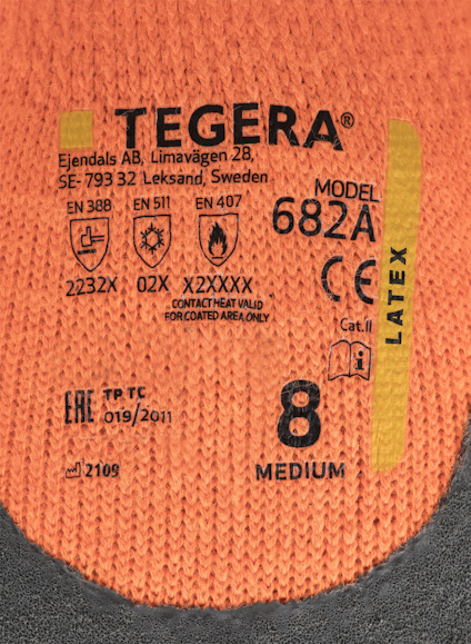 Orange och svart arbetshandske med text: "Ejendals AB Tegera 682A, CE, EN 511, EN 407, Medium 8, Latex".