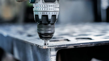 Borrmaskin borrar i metallplåt på nära håll.