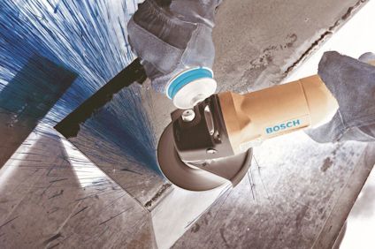 Vinkelslip med gnistor, hålls i en handskbeklädd hand, bearbetar en metallbit. Märket Bosch synligt på verktyget.