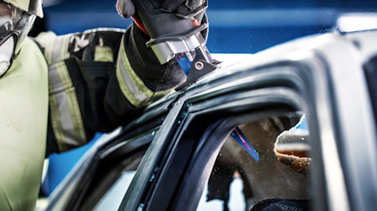 Brandman i uniform använder hydrauliskt verktyg på bilens dörr.