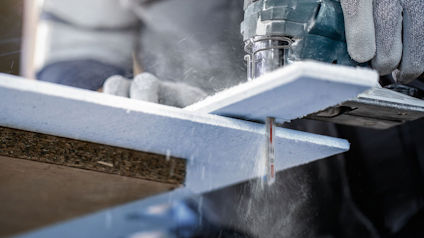 En person sågar en vit panel med en elektrisk sticksåg.