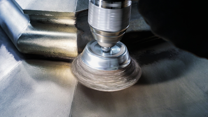 Metallborste fäst på en borrmaskin polerar en metallisk yta.