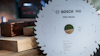 Cirkelsågklinga med text: "Bosch PRO Wood". Bakgrund med träplankor.